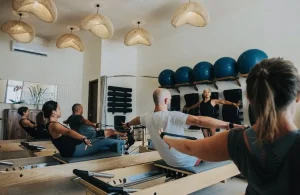 A diverse group of men and women in a reformer Pilates class led by an instructor at the welcoming Basi Pilates Studio in Canggu.
