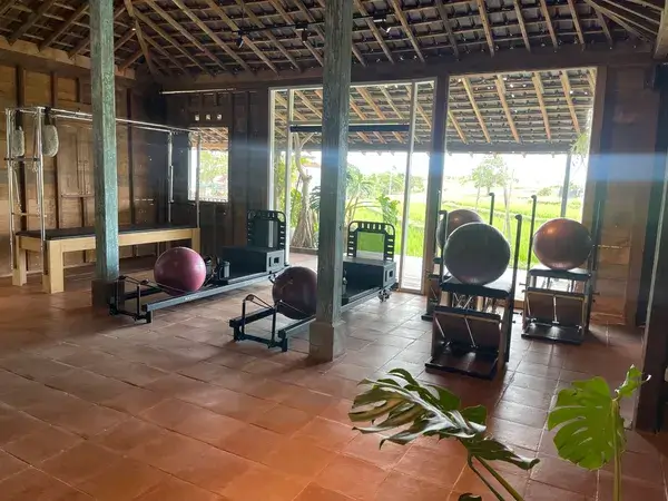 The serene and rustic interior of Lilates Pilates studio in Canggu, featuring wooden architecture and a beautiful view of a rice paddy.