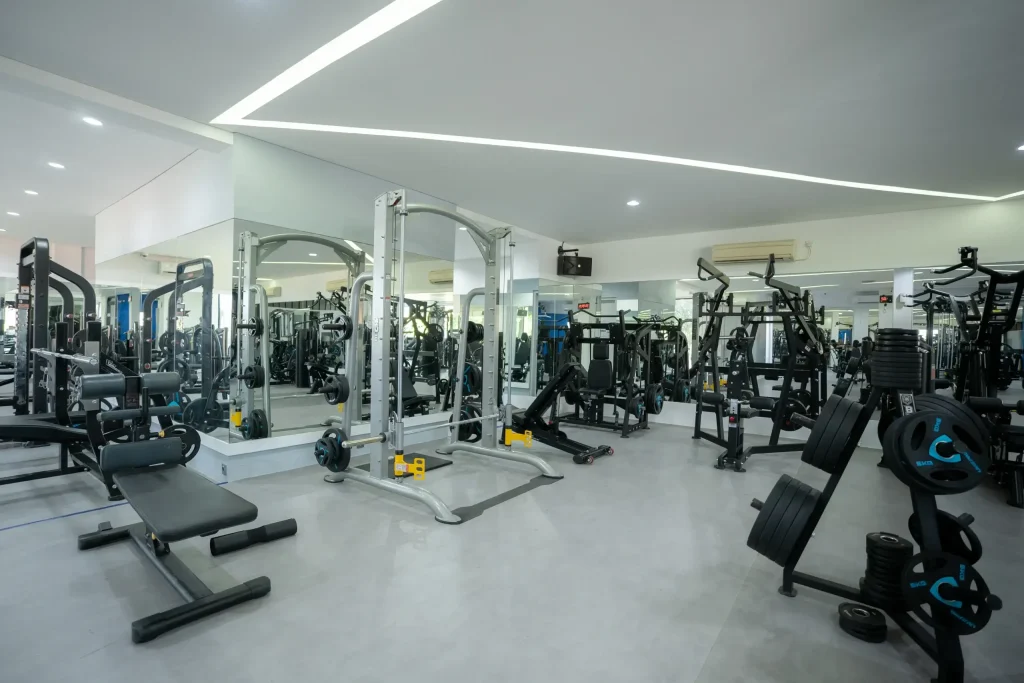 A wide view of the main strength training and free weight area on the second floor of Avenue Fitness Canggu, featuring a Smith machine, plate loaded equipment, and weight benches.