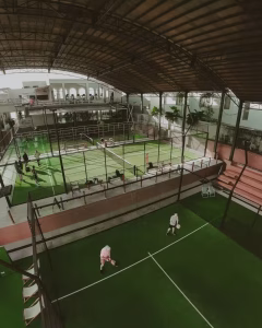 A high-angle view of the expansive Bali Social Club, showing multiple green padel courts with games in progress and spectator areas.