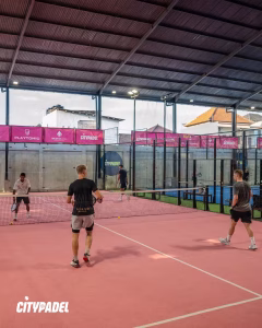 Four men engaged in a competitive doubles match on the unique pink padel court at CityPadel in Bali.