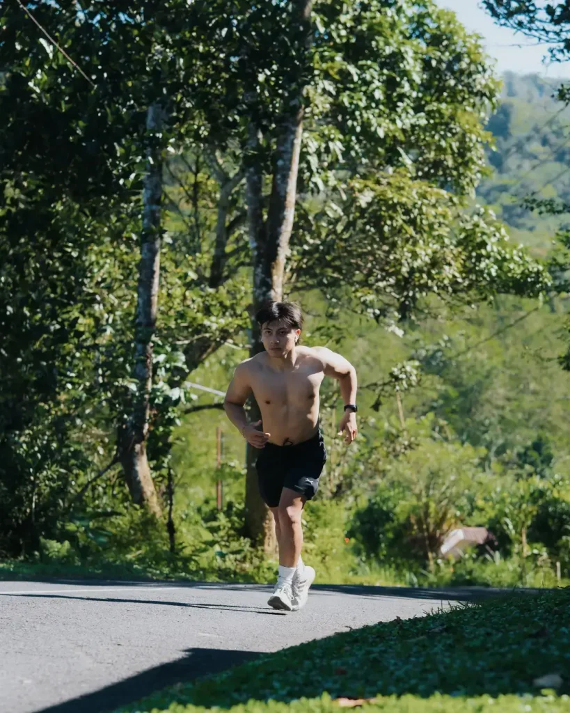 An athletic participant running on a road surrounded by lush greenery during the ARC Farm Trail Run event in the Bali countryside on July 20 2025.