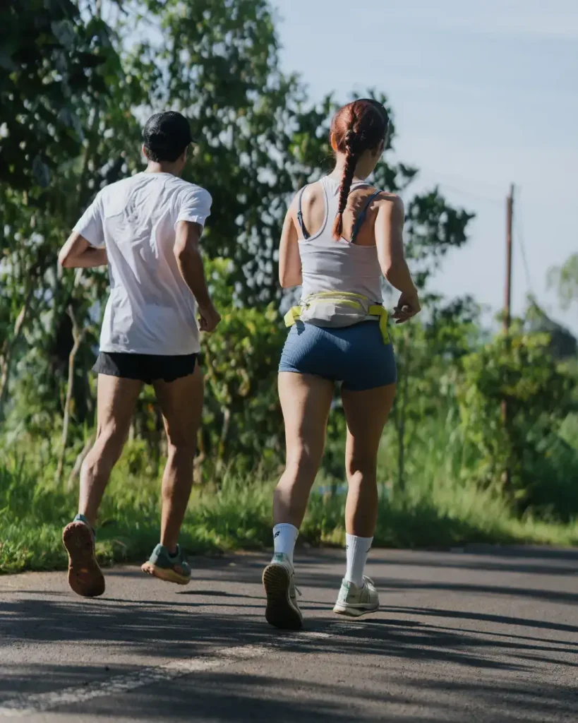 Two participants running side by side on a scenic road during the Farm Trail Run event in Jempanang, Bali, on June 15 2025.