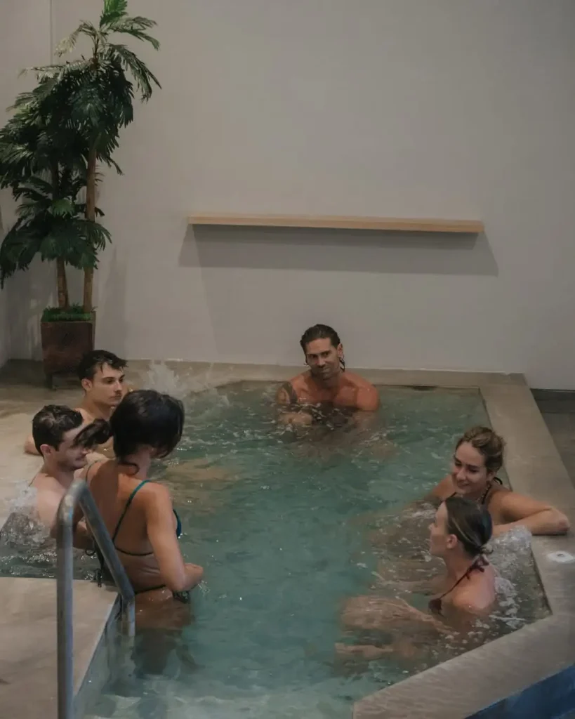 A group of members socializing and relaxing in the large cold plunge pool in the recovery zone at Avenue Fitness Canggu.