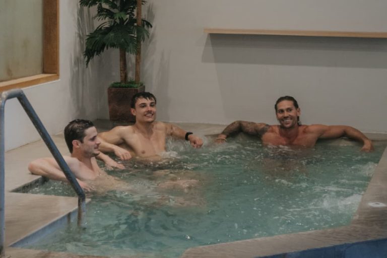 Three men enjoying cold water immersion for post-workout recovery, experiencing icebath benefits for muscle repair.