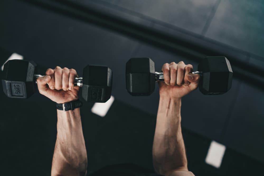 Close-up of a man's arms lifting weights, a core exercise in effective dumbbell workouts for building upper body strength.
