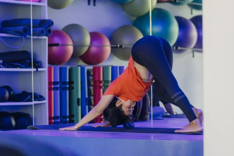 Woman performing downward dog pose during a gentle hatha flow session in a yoga studio.