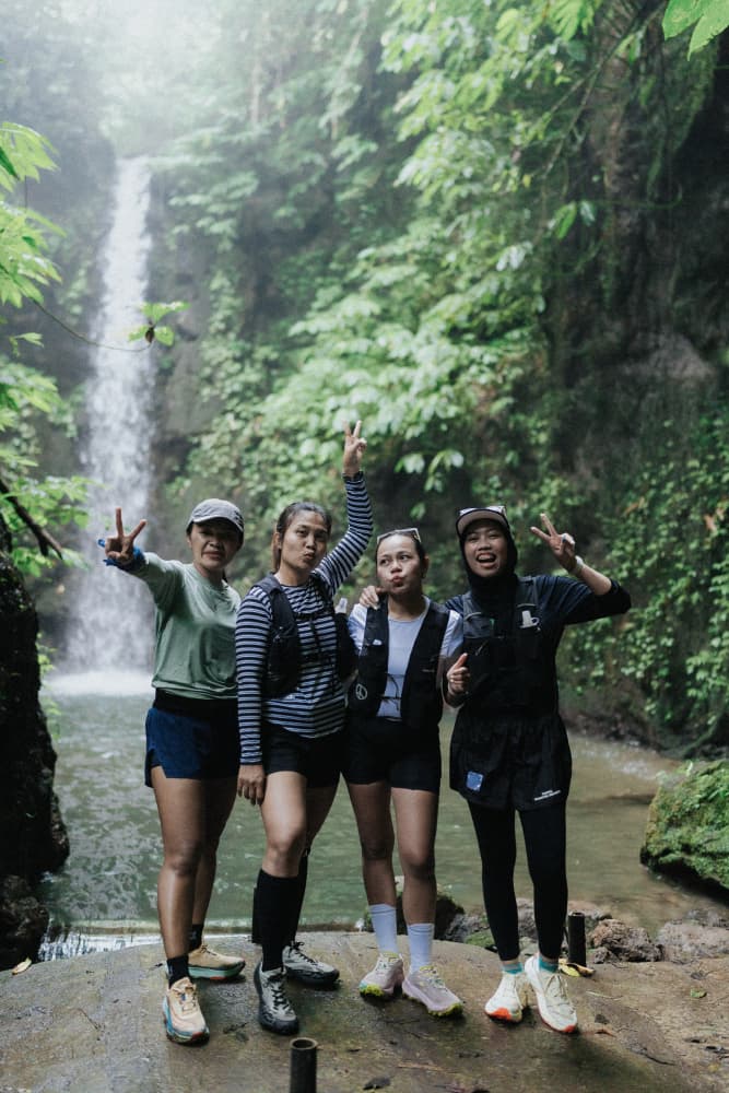 Four women hikers pose together in front of a cascading waterfall during the Avenue Fitness Naturun event.
