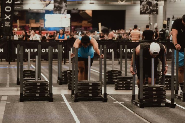 Athletes pushing heavy weight sleds during a HYROX competition indoors.