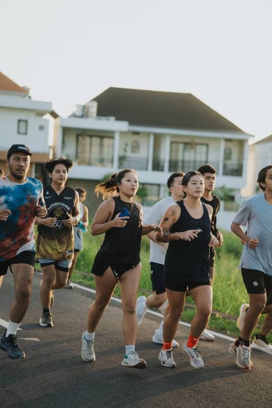 A group of joggers from the Avenue Running Club running together on a street in canggu.